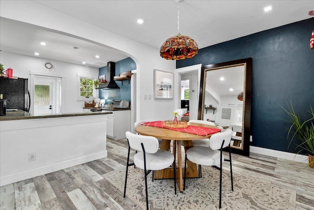 dining area with arched walkways, recessed lighting, baseboards, and light wood-style floors