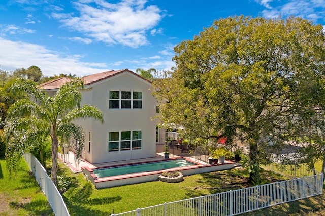 back of property featuring stucco siding, a fenced backyard, a yard, a fenced in pool, and a tiled roof