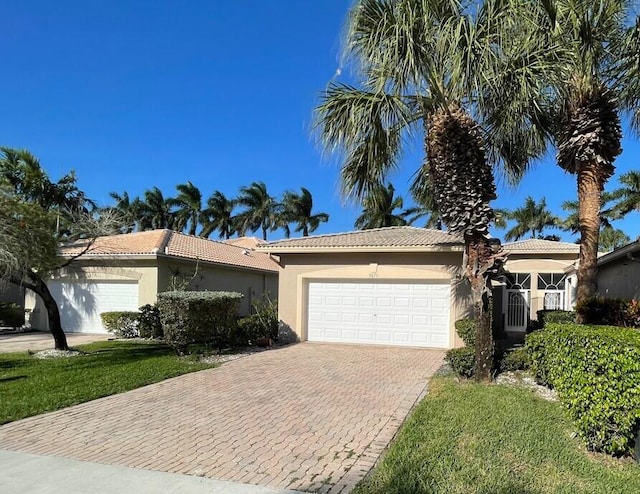 ranch-style house featuring a tiled roof, decorative driveway, a garage, and stucco siding