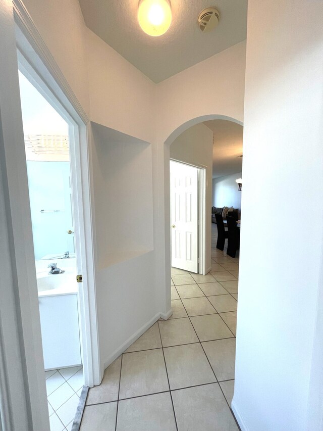 9675 Crescent View Dr N, Boynton Beach, FL 33437 - hall featuring arched walkways, light tile patterned floors, and baseboards
