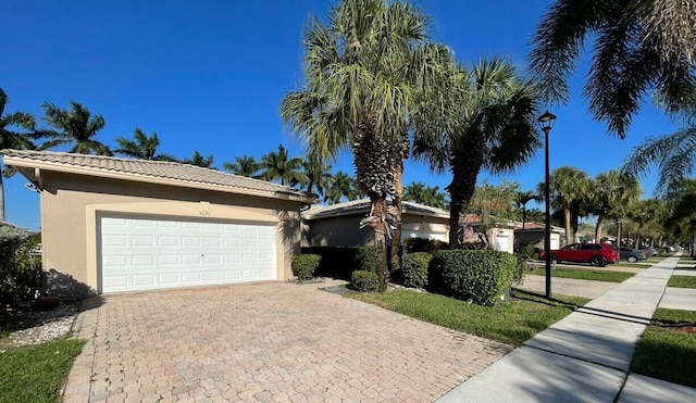 ranch-style home featuring a tiled roof, decorative driveway, and stucco siding