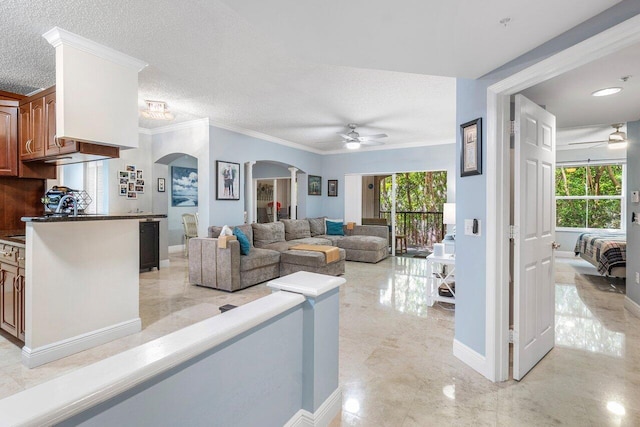 living area with a ceiling fan, arched walkways, and a healthy amount of sunlight