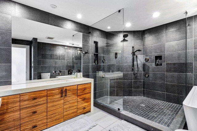 bathroom with tile walls, toilet, a tile shower, recessed lighting, and vanity