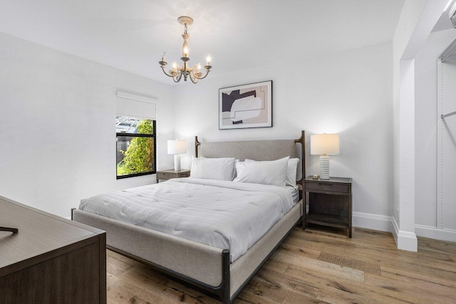 bedroom featuring baseboards, a notable chandelier, and wood finished floors