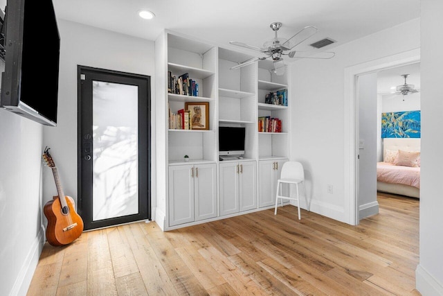 interior space with a ceiling fan, visible vents, light wood finished floors, and baseboards