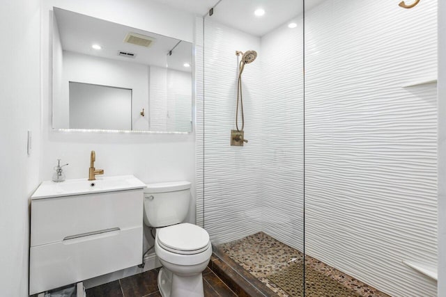 bathroom featuring vanity, toilet, a walk in shower, and visible vents