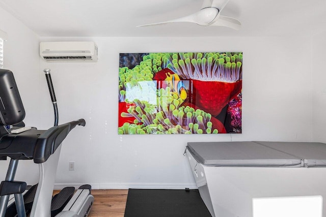 exercise room featuring baseboards, wood finished floors, a ceiling fan, and a wall mounted AC