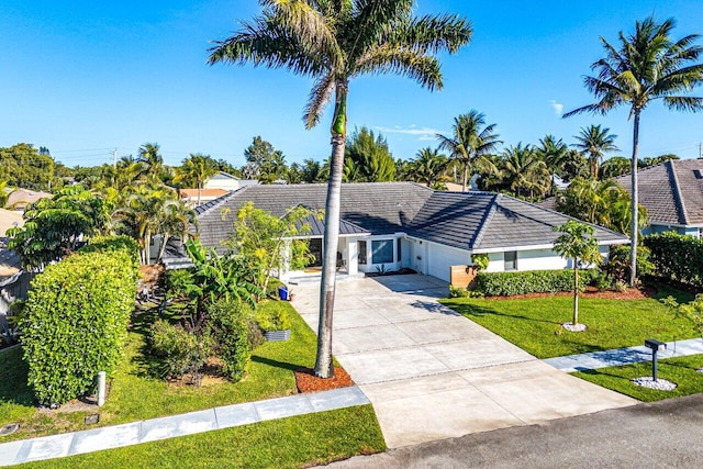 single story home with concrete driveway, a tiled roof, and a front lawn