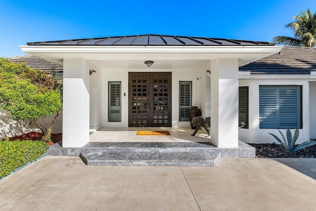 property entrance featuring stucco siding, a porch, metal roof, and a standing seam roof