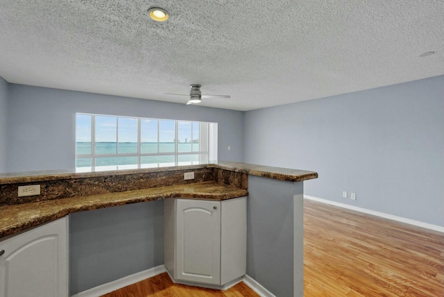 kitchen featuring white cabinetry, light wood-type flooring, and baseboards