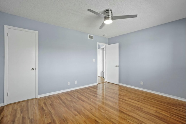 unfurnished bedroom featuring a ceiling fan, baseboards, wood finished floors, visible vents, and a textured ceiling