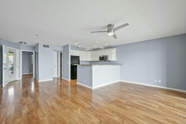 unfurnished living room featuring baseboards, visible vents, a ceiling fan, and light wood-style floors