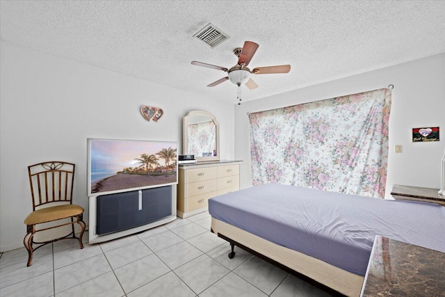 bedroom with light tile patterned floors, a ceiling fan, visible vents, and a textured ceiling