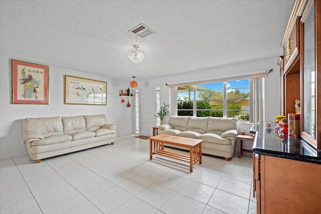 living area with light tile patterned flooring, visible vents, and a textured ceiling