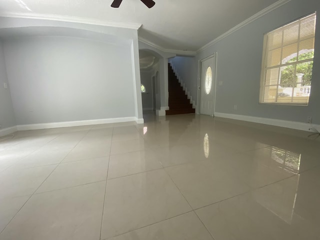 interior space featuring stairs, a ceiling fan, baseboards, and ornamental molding