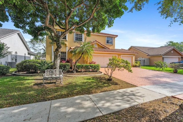 mediterranean / spanish-style home with fence, a tiled roof, a front yard, stucco siding, and decorative driveway