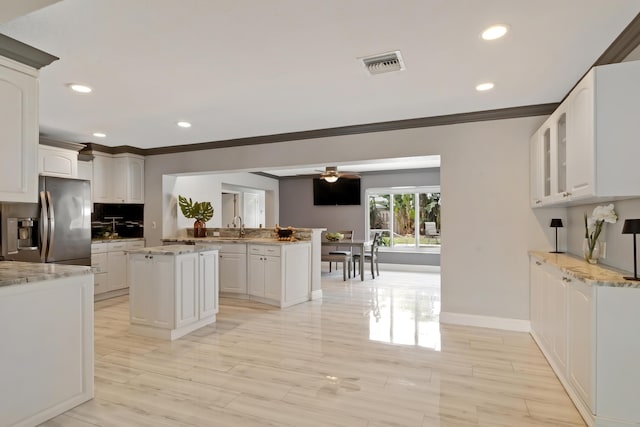 kitchen with visible vents, stainless steel fridge, white cabinetry, and decorative backsplash