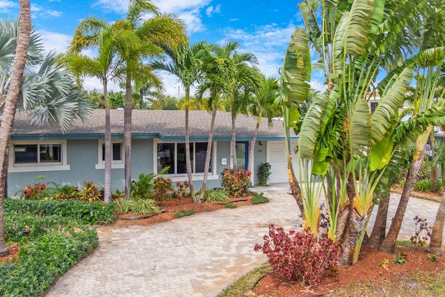 single story home featuring stucco siding, a shingled roof, decorative driveway, and a garage