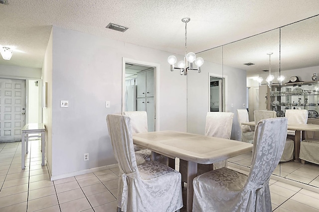 dining room with a textured ceiling, light tile patterned flooring, baseboards, and a chandelier