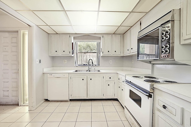 kitchen with white appliances, light tile patterned floors, a drop ceiling, a sink, and light countertops