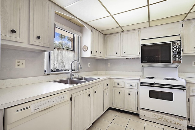 kitchen featuring a drop ceiling, light countertops, light tile patterned flooring, white appliances, and a sink