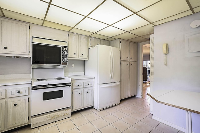 kitchen featuring light tile patterned flooring, a drop ceiling, white appliances, and light countertops