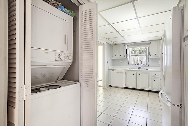 washroom with laundry area, light tile patterned flooring, stacked washer and clothes dryer, and a sink