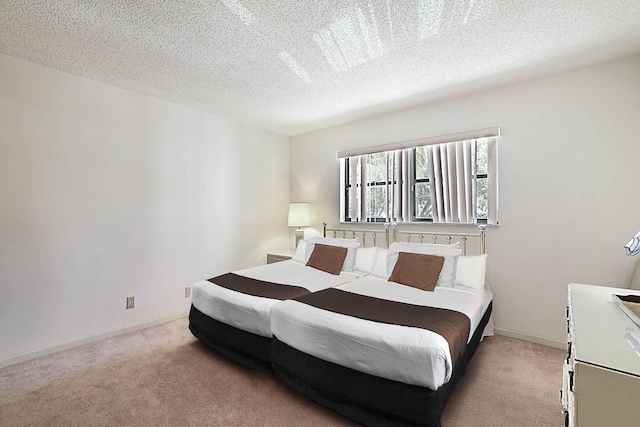 bedroom featuring light colored carpet, a textured ceiling, and baseboards