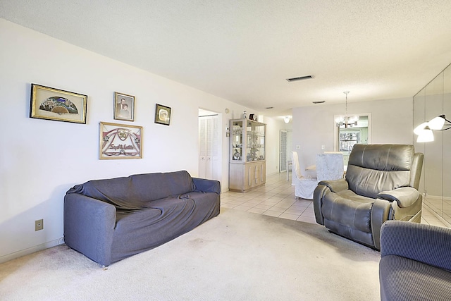 living area featuring visible vents, light carpet, an inviting chandelier, light tile patterned flooring, and a textured ceiling