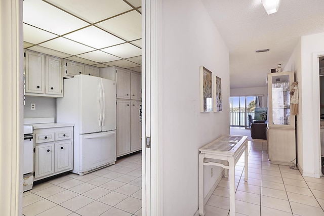 kitchen featuring light tile patterned flooring, light countertops, freestanding refrigerator, and stove