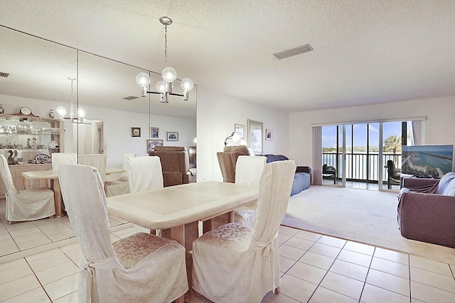 dining space featuring light tile patterned floors, visible vents, an inviting chandelier, a textured ceiling, and light colored carpet