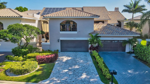 mediterranean / spanish home with stucco siding, decorative driveway, a chimney, and a tiled roof