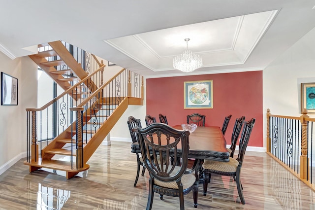 dining area with a tray ceiling, baseboards, a notable chandelier, and ornamental molding