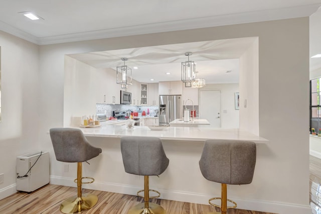 kitchen featuring backsplash, glass insert cabinets, light countertops, appliances with stainless steel finishes, and a peninsula