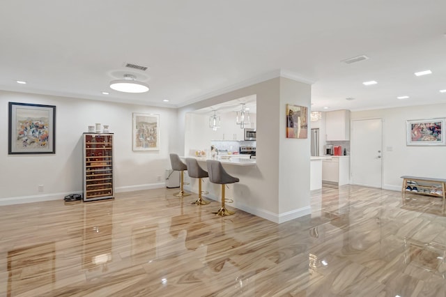 kitchen with visible vents, beverage cooler, a kitchen breakfast bar, white cabinets, and stainless steel appliances