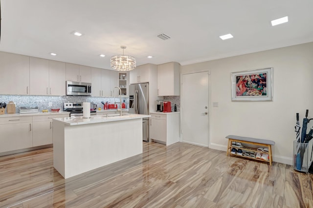 kitchen featuring visible vents, backsplash, decorative light fixtures, light countertops, and appliances with stainless steel finishes