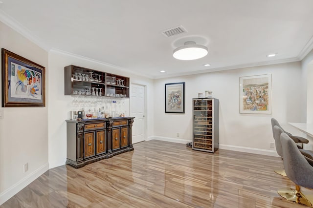 bar with visible vents, crown molding, baseboards, beverage cooler, and a dry bar