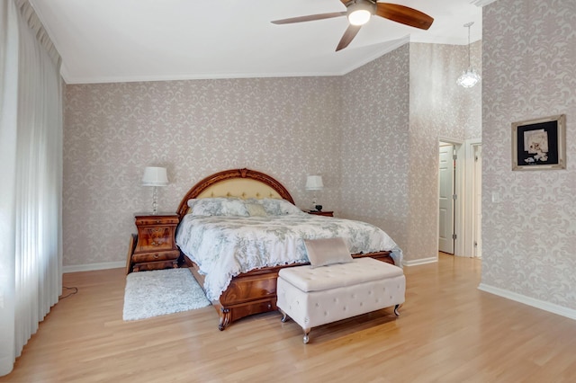 bedroom featuring baseboards, wood finished floors, ornamental molding, and wallpapered walls