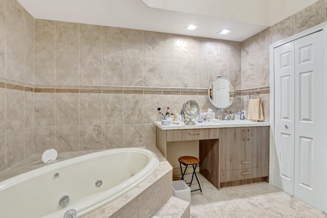 bathroom with vanity, tile walls, a whirlpool tub, and tile patterned flooring