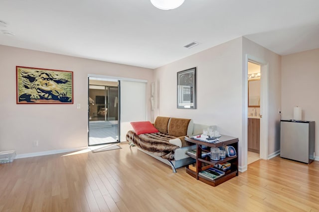 living room featuring light wood-type flooring, baseboards, and visible vents