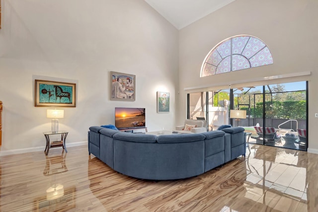 living area featuring light wood-type flooring, baseboards, and high vaulted ceiling