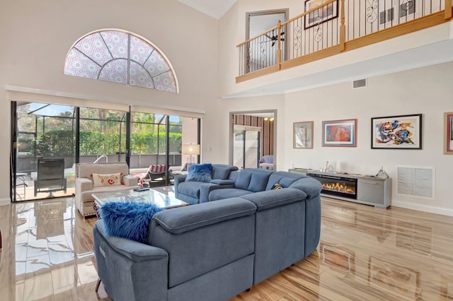 living room with visible vents, baseboards, a glass covered fireplace, and crown molding