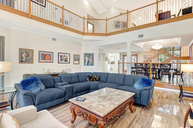 living area featuring a chandelier, visible vents, a towering ceiling, and wood finished floors