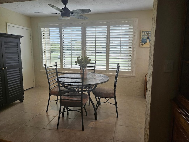 tiled dining room with a textured ceiling, a textured wall, and ceiling fan