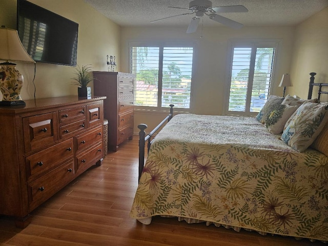 bedroom featuring a ceiling fan, light wood-type flooring, and a textured ceiling