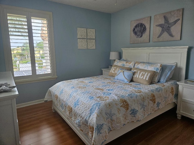 bedroom featuring wood finished floors, baseboards, and a textured ceiling