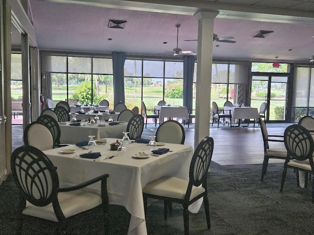 dining room featuring visible vents, a ceiling fan, expansive windows, a textured ceiling, and wood finished floors