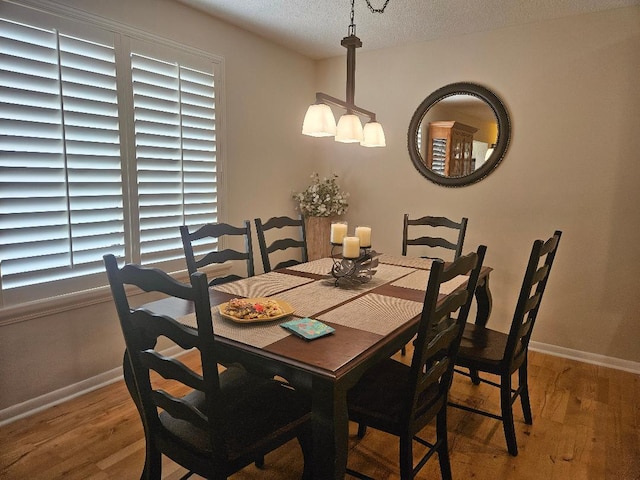 dining area featuring light wood-style floors, baseboards, and a textured ceiling