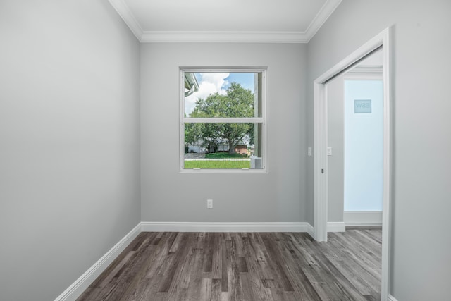 spare room featuring crown molding, baseboards, and wood finished floors