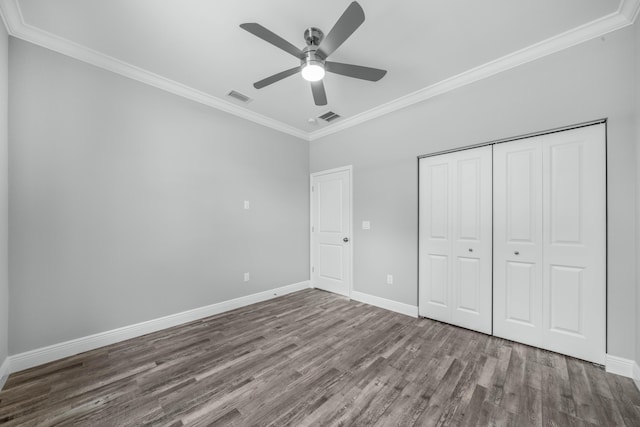 unfurnished bedroom with visible vents, crown molding, and wood finished floors